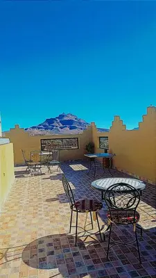 a patio with tables and chairs and a mountain in the background at Riad Tazoulte in Agdz