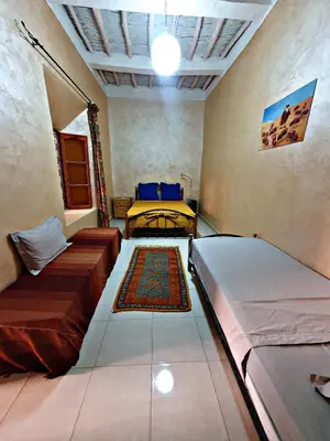 a room with two beds and a rug at Riad Tazoulte in Agdz