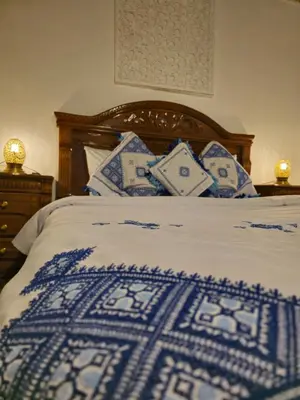 a bed with blue and white sheets and pillows at Ryad Zahrat Fes in Fès