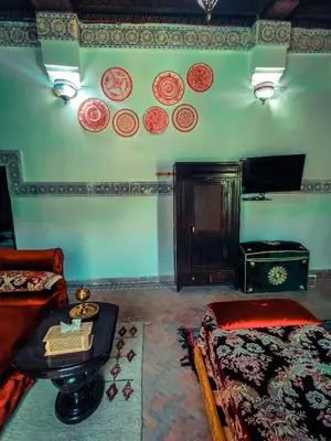 a room with a bed and a table and plates on the wall at Ryad Zahrat Fes in Fès