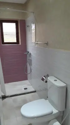 a bathroom with a toilet and a shower with a red door at Le Chêne d´Azrou in Azrou