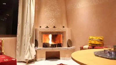 a fireplace in a living room with a table at Le Chêne d´Azrou in Azrou