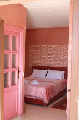 a bedroom with a bed and a pink door at Le Chêne d´Azrou in Azrou