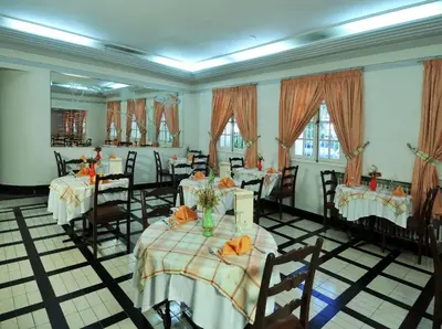 a dining room with tables and chairs and windows at Hotel Splendid in Fès
