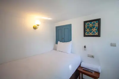 a white bedroom with a bed and a blue door at Cine House in Fès