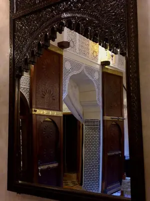 a mirror with a reflection of a building in it at Riad Benchekroun in Meknès