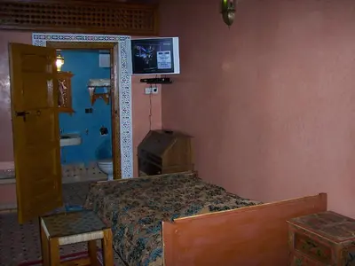 a bedroom with a bed and a tv on the wall at Riad Benchekroun in Meknès