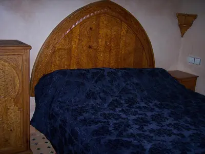 a bedroom with a large wooden bed with a blue blanket at Riad Benchekroun in Meknès