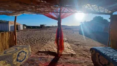 a tent on a beach with the sun behind it at Desert Atmosphere M'Hamid in Mhamid