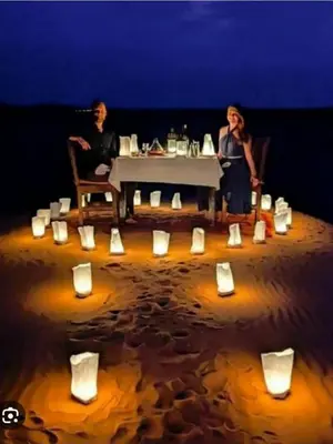 two people sitting at a table with cups and candles at Erg Chebbi Luxury Camp in Merzouga