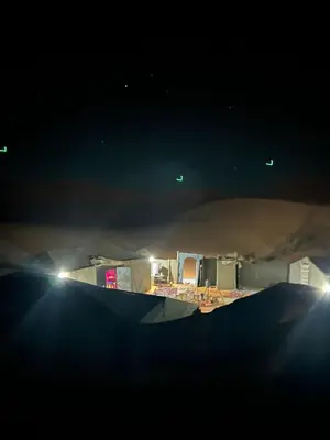 a view of a desert at night with lights at Merzouga Camp and Hostel in Merzouga