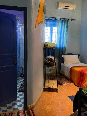 a bedroom with a bed and a room with a door at Merzouga Camp and Hostel in Merzouga