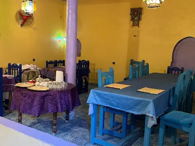a dining room with blue tables and chairs at Merzouga Camp and Hostel in Merzouga