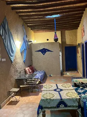 a room with two beds and a table and chairs at Merzouga Camp and Hostel in Merzouga