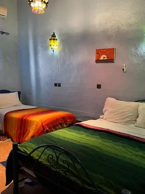 two beds with colorful sheets in a room at Merzouga Camp and Hostel in Merzouga
