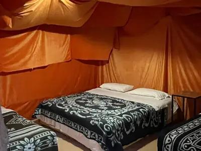 a room with two beds in a tent at Merzouga Camp and Hostel in Merzouga