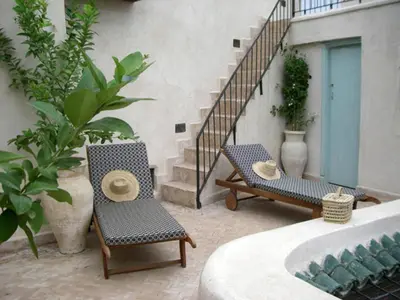 a patio with two chairs and stairs with plants at Dar Eva in Fès