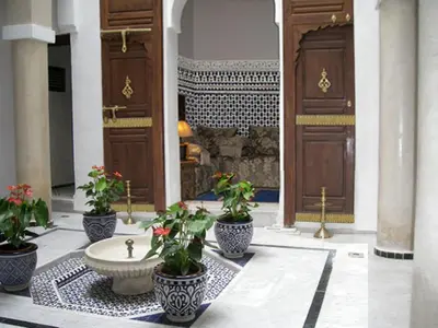 a lobby with a fountain and potted plants in a building at Dar Eva in Fès