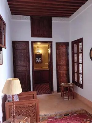 a living room with wooden doors and a lamp at Dar Eva in Fès