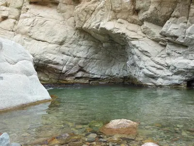 a pool of water in front of a rocky cliff at Au Bord de l'Eau in Setti Fatma