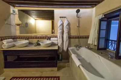 a bathroom with two sinks and a tub and a mirror at Riad Braya in Fès