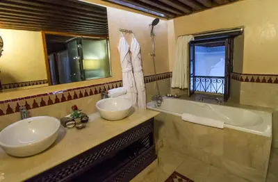 a bathroom with two sinks and a tub and a window at Riad Braya in Fès