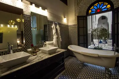 a bathroom with two sinks and a tub and a window at Riad Braya in Fès