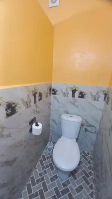 a bathroom with a white toilet in a yellow wall at Nomad Bivouac in Merzouga