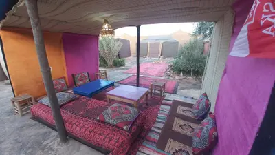 a tent with a bed and a table and chairs at Nomad Bivouac in Merzouga