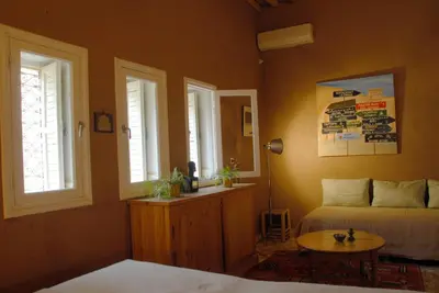 a bedroom with a bed and a table and windows at Villa Zagora Ma Villa au Sahara in Zagora