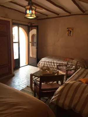 a bedroom with two beds and a table and a chandelier at Riad Dar Bergui in Ouarzazate