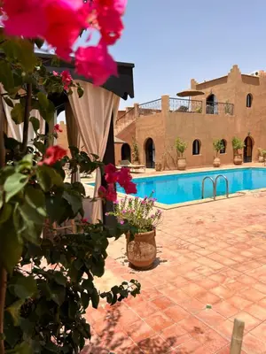 a courtyard with a pool and some flowers and a building at Riad Dar Bergui in Ouarzazate