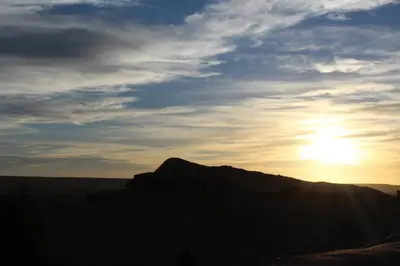 a sunset in the desert with the sun in the sky at Maison d'Hôtes Nouflla in Aït Ben Haddou