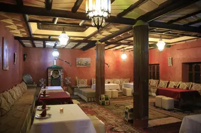 a large room with couches and tables and a fireplace at Maison d'Hôtes Nouflla in Aït Ben Haddou