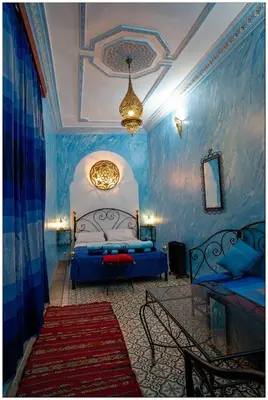 a blue bedroom with a bed and a chandelier at Riad Fés blida in Fès