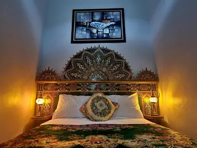 a bed with a large wooden headboard in a bedroom at Riad Fés blida in Fès