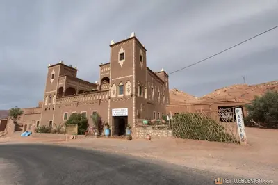 a large brick building on the side of a road at Kasbah Ounila in Aït Ben Haddou