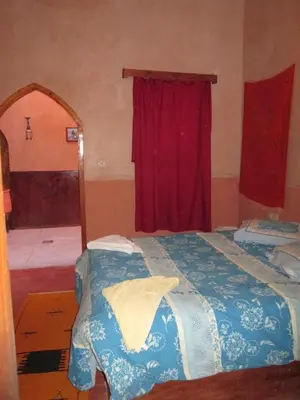 a bedroom with a bed and a red curtain at Kasbah Ounila in Aït Ben Haddou