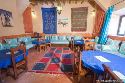 a dining room with blue tables and blue chairs at Kasbah Ounila in Aït Ben Haddou