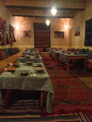 a group of tables in a large room with plates on them at Kasbah Ounila in Aït Ben Haddou