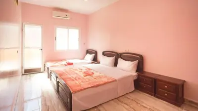 two beds in a bedroom with pink walls at Kasbah Hotel Camping Jurassique in Ifri