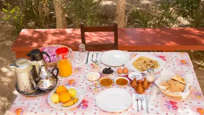 a table with plates of food and fruit on it at Kasbah Hotel Camping Jurassique in Ifri