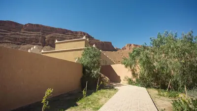 a path in the desert with a mountain in the background at Kasbah Hotel Camping Jurassique in Ifri