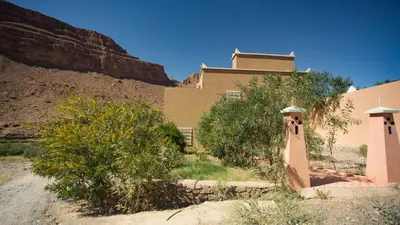 a building in the middle of a desert with a mountain at Kasbah Hotel Camping Jurassique in Ifri