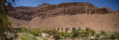 a building in front of a rocky mountain at Kasbah Hotel Camping Jurassique in Ifri