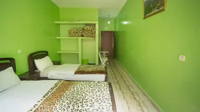 two beds in a room with green walls at Kasbah Hotel Camping Jurassique in Ifri