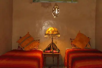 a room with two beds and a lamp on a table at Kasbah Dar Dmana in Skoura