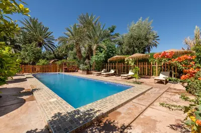 a swimming pool in a yard with a fence at Ecolodge La Palmeraie in Ouarzazate