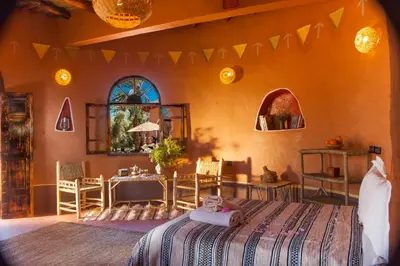 a bedroom with a bed and a table and chairs at Ecolodge La Palmeraie in Ouarzazate