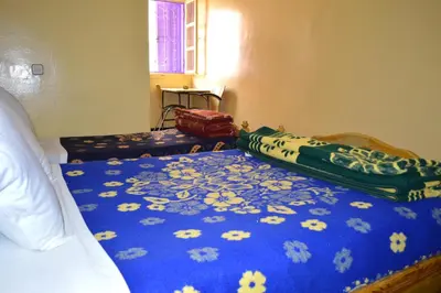 a bedroom with a bed with a blue blanket with flowers at Hotel Atlas Ouarzazate in Ouarzazate